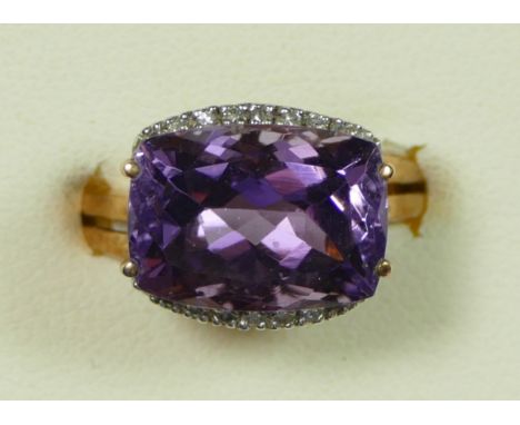 A 9K gold, amethyst and brilliant cut diamond dress ring, claw set with a mixed cut stone, flanked by diamonds, raised pierce