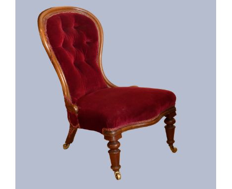 A Victorian mahogany framed nursing chair, having spoon button back, upholstered in a burgundy drylon fabric, raised on turne