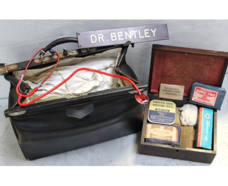 A c1940s black leather doctors' bag containing a quantity of medical equipment to include gowns, plastic aprons, blood pressu