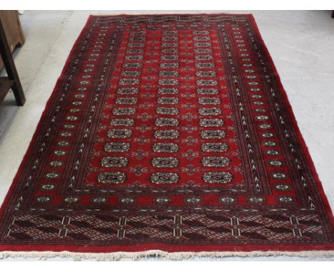 A red ground Bokhara carpet with multiple gul decorations within a geometric multi-border, 260 x 153cm.