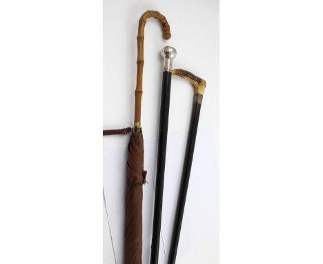 A gentlemen's silver-topped ebonised walking cane, hallmarked Chester 1902, a bamboo-handled vintage umbrella and an antler-h