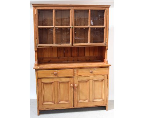 A Victorian pine dresser, twin sectional glazed doors with one interior shelf, over two frieze drawers to two panelled cupboa