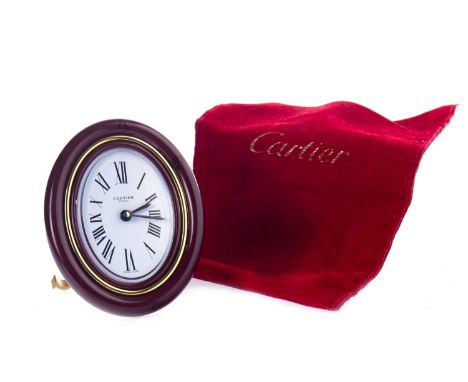 CARTIER ALARM CLOCK, serial no. 7519 15231, the white oval dial with Roman numerals inscribed 'Cartier', within a burgundy an