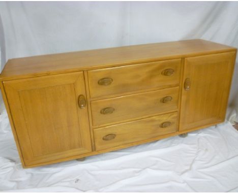 A 1960's Ercol light elm sideboard with three central drawers flanked by cupboards enclosed by two panelled doors