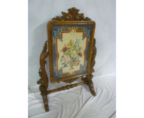 A Victorian carved walnut rectangular fire screen with inset needlework, tapestry panel on scroll supports