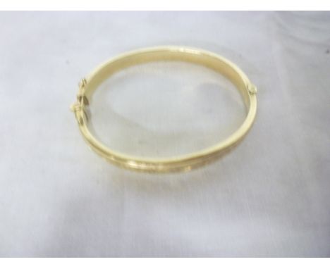 A 9ct gold oval bangle with engraved decoration