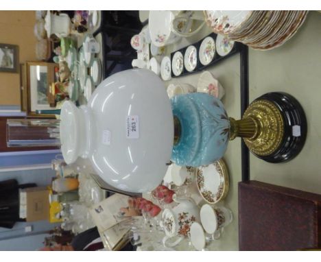 A VICTORIAN OIL LAMP, CLEAR GLASS FLUE, MILKY WHITE GLASS SHADE, BLUE GLASS OIL WELL, ON BRASS STAND RAISED ON BLACK CERAMIC 