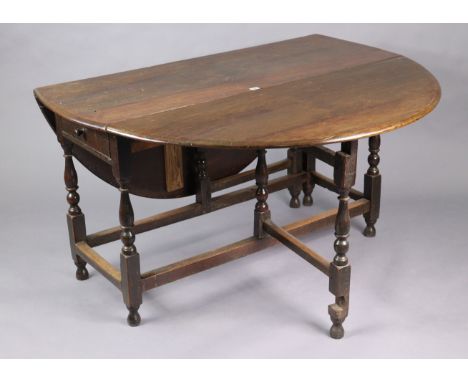 A 1930’s oak oval gate-leg dining table fitted end drawer, &amp; on baluster-turned legs &amp; turned feet with plain stretch