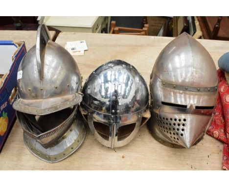 Three medieval style steel helmets, comprising a close helmet with high comb, a basinet and a Norman type helmet with hinged 