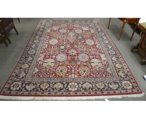 Good European machine made carpet of Agra design, the brick red field with an allover design of large palmettes within indigo