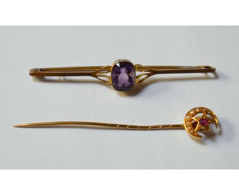 A yellow metal bar brooch set with a central amethyst, stamped 9ct, 5.5 cm long, approx 2.2g all in to/w stick pin with garne