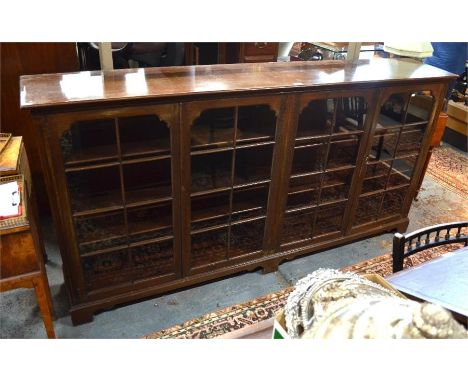 A mahogany low library bookcase with four astragal glazed cabinet doors enclosing adjustable shelves, raised on shaped bracke