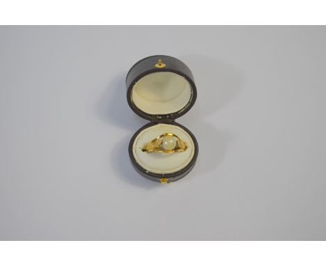 A Continental Egyptian Revival yellow metal ring formed of two engraved serpents clasping a cultured pearl, size M