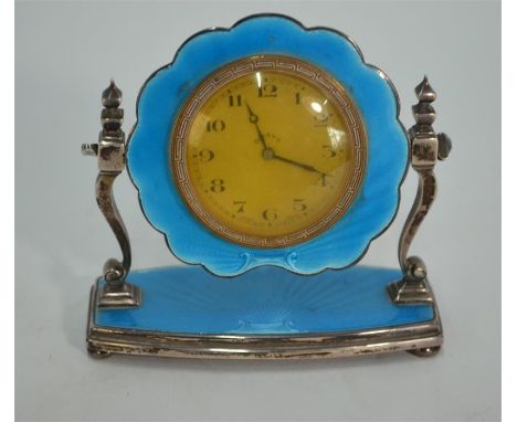 An Art Deco silver and basse-taille blue enamel boudoir clock with gilt and enamel bezel, swinging on scroll pillars and plat