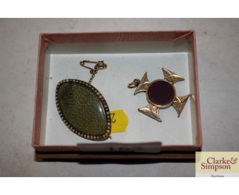 An oval yellow metal brooch with seed pearl surround; and a yellow metal Maltese Cross shaped brooch with central mauve stone