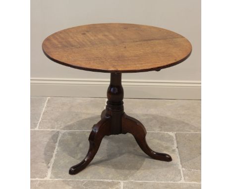 A George III oak tripod table, the circular top raised upon a ring turned baluster column, extending to down swept supports a