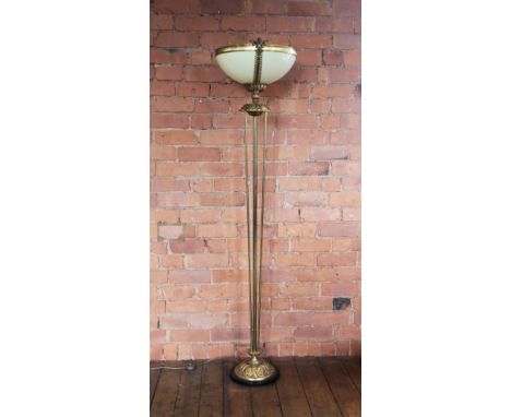 An Art Deco style brass floor standing uplighter, late 20th century, the yellow moulded bowl set to a floral collar raised on
