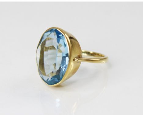 An 18ct gold paste set cocktail ring, the central oval mixed cut blue paste (measuring 20mm x 14mm), bezel set to tapered sho