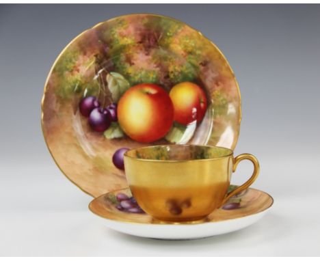 A Royal Worcester porcelain trio, mid 20th century, comprising a teacup, the interior hand painted with fruits on a naturalis