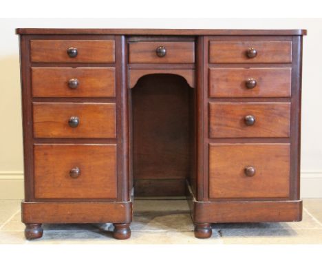 A Victorian mahogany kneehole dressing table, the arched mirrored plate raised upon carved supports and banks of small drawer