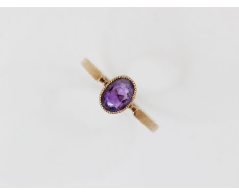 A late Edwardian amethyst set 9ct gold ring, the central oval mixed cut amethyst (measuring 6.5mm x 4.5mm), bezel set 9ct gol