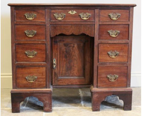 A George III mahogany kneehole desk, with an arrangement of nine drawers embracing the central recessed cupboard door, raised