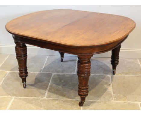 A Victorian oak extending dining table, the oval top raised upon substantial ring turned tapering legs and ceramic castors, w