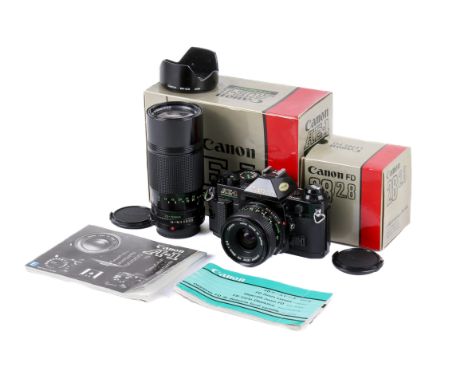 A Canon AE-1 Program 35mm SLR camera outfit. Black body. Serial number 1997414. With two lenses; a Canon FD 28mm f2.8 and a C