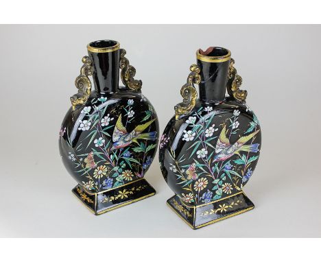 A pair of Victorian pottery moon flasks with bright enamel decoration of birds and insects in foliage, on black ground with g