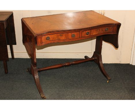 A mahogany sofa table with burr wood cross-banded serpentine top, two frieze drawers and opposing dummy drawers, on twin end 