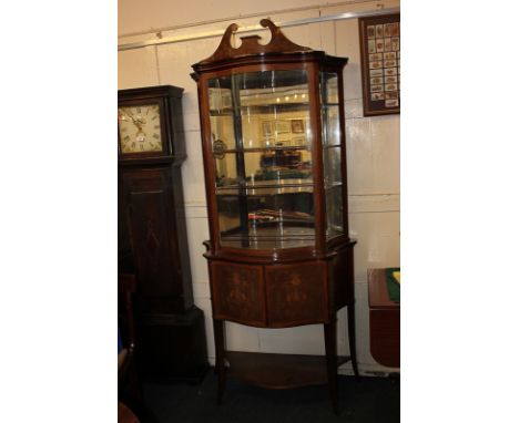 An Edwardian mahogany display cabinet, inlaid with floral, urn and scroll detail, the bow front single glazed door enclosing 