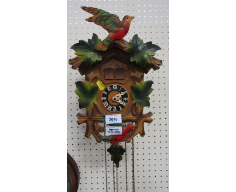 A cuckoo clock, in beech casing with applied green maple leaves and birds, with weights.