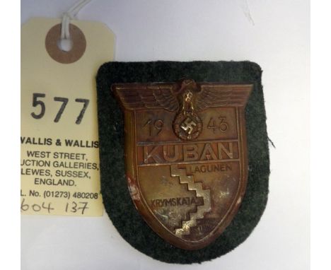 A Third Reich Kuban arm shield,  of bronzed zinc on field grey cloth patch with backing plate and paper backing. GC          