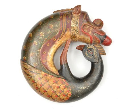 An Indian carved and painted circular wooden powder flask. In the form of a makarra,18cms, the tail formed as bird. G.C. (not