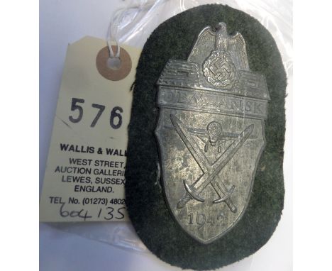A Third Reich Demjansk arm shield,  of zinc on field grey cloth patch with backing plate. GC