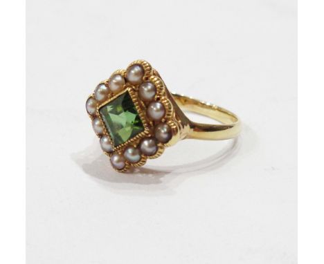 A marked 18ct yellow metal square panel ring, set with central peridot within a seed pearl border - size N