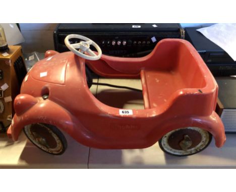 A vintage child's pedal car with red plastic body and rubber tyres