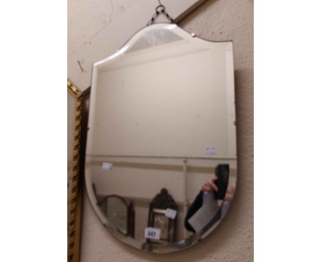 A vintage frameless shield shaped wall mirror with bevelled plate