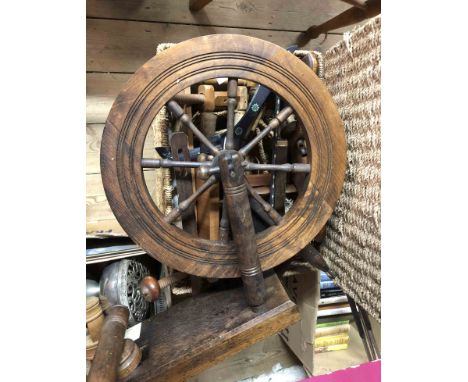A vintage wooden spinning wheel - sold with a lidded wicker basket containing associated parts and equipment, etc.
