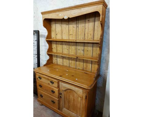 A 1.2m antique waxed pine two part dresser with two shelf open plate rack over a base with three graduated drawers to one sid