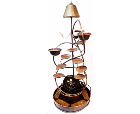 A 1.5m high freestanding copper water feature/standard lamp with a cascade of dishes and waterwheel under, set in a large cir