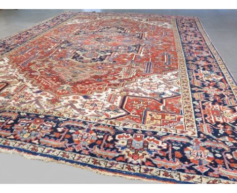 Antique Persian Heriz carpet with central red ground and blue and red borders 3.75 x 2.81m