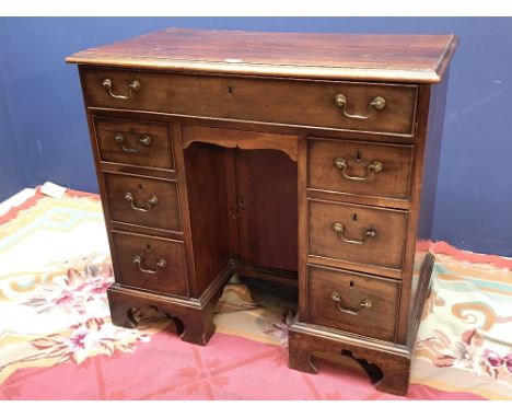 George III mahogany kneehole desk with rectangular top and seven drawers of various size about the recessed cupboard upon bra
