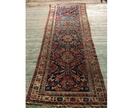Antique Caucasian runner with central panel of motifs in strong colours on dark navy blue ground and geometric border with mo
