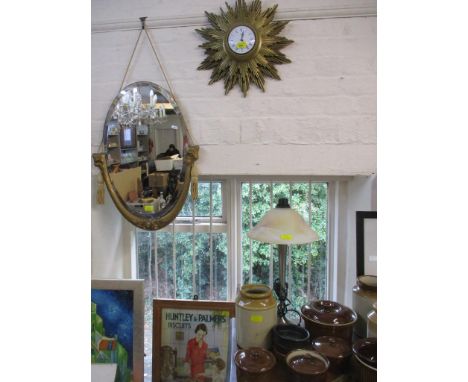 A Metamee quartz Sunburst clock, a gilt framed wall mirror, bevelled glass and fabric tassels, and a modern table lamp with d