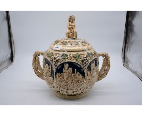 A German stoneware Castle Pot with Putti sitting on the lid, 13 1/2" tall.