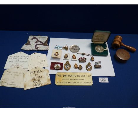 A box of miscellaneous enamel badges and an auctioneers gavel.