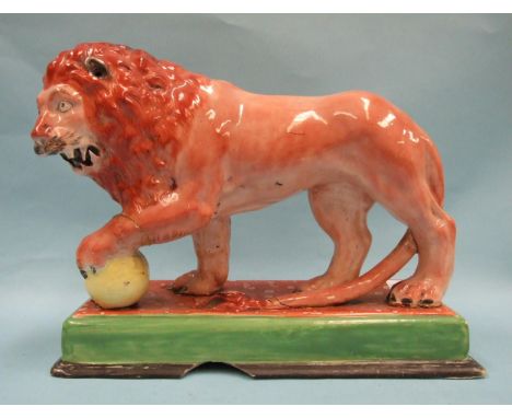An early Staffordshire model of a Medici lion, with left paw on a globe, on oblong plinth, 31cm long, 24cm high. 