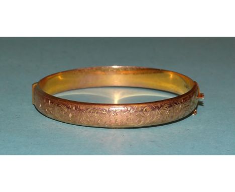 A 9ct gold hinged bangle with engraved decoration, internal dimensions 6 x 5.3cm, 10g. 