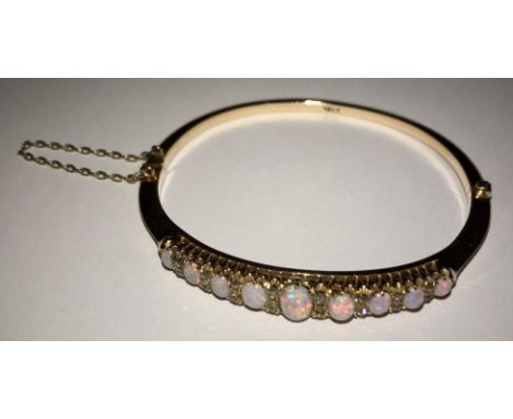 A 15ct bangle set with nine graduated fine opals and eighteen old cut diamonds, total weight of bangle 11.5g 